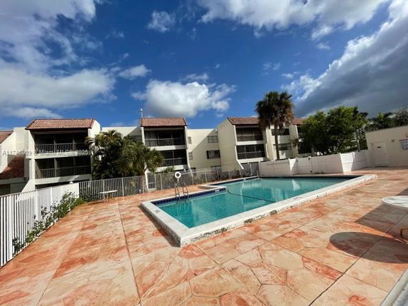Outdoor swimming pool area with surrounding buildings.