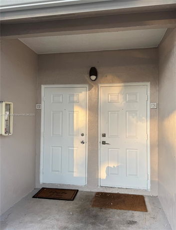 Front view of a house entrance with two white doors and welcome mats.
