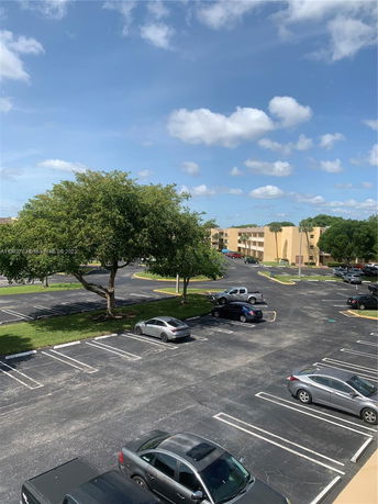 View of a parking area with several cars parked under a clear sky.