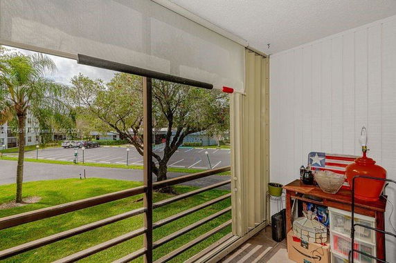 View from a balcony overlooking a parking area and trees.