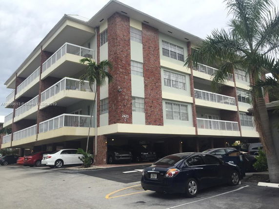 Front view of a multi-story building with parking area.