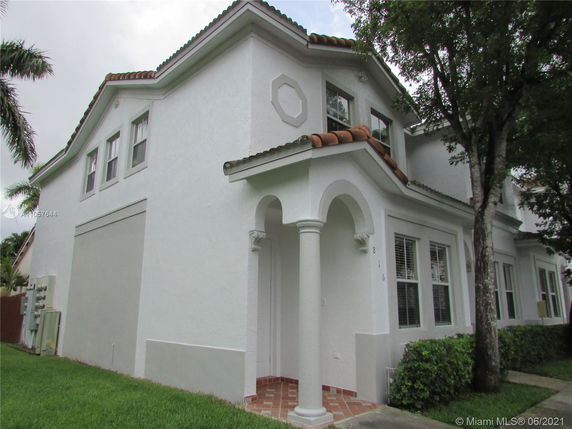Front view of a two-story house with arched entryway and tiled roof.