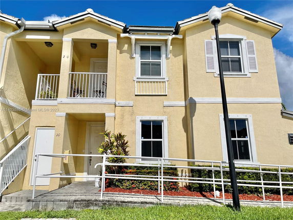 Front view of a two-story building with balconies and a ramp leading to the entrance.