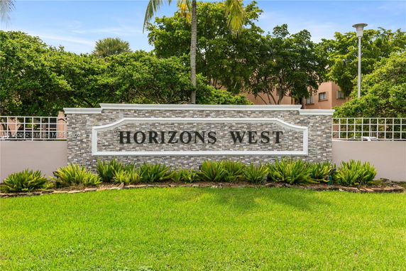 Front view of a building sign reading 'Horizons West' with plants in front.