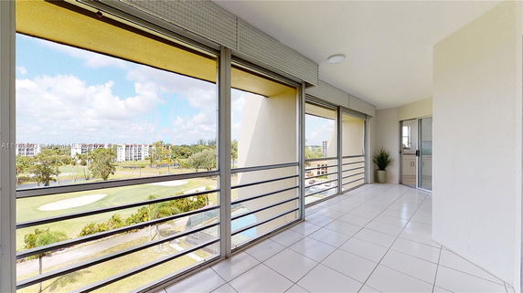 View from a balcony with railings, overlooking a golf course and nearby buildings.
