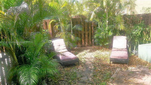 Outdoor area with lounge chairs surrounded by dense greenery.