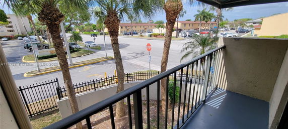 View of a residential area with palm trees and parking spaces, seen from a balcony.