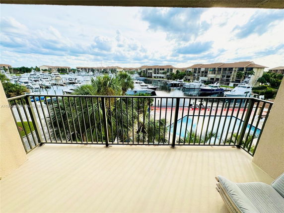 View from a balcony overlooking a marina with boats and buildings in the background.