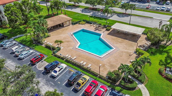 Aerial view of a swimming pool area with surrounding deck and parking spaces.