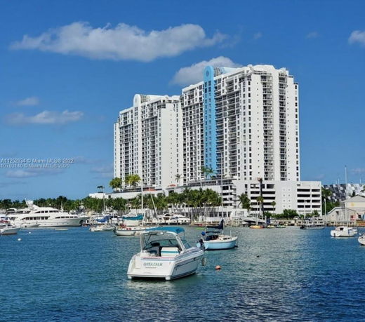 Front view of a tall apartment building beside a marina.