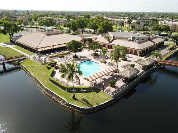 Aerial view of a recreational area with a large pool, surrounded by buildings and greenery.