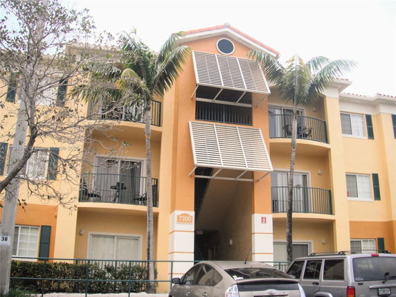 Front view of a multi-story apartment building with balconies and an entrance.