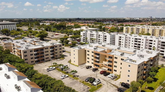 Aerial view of multiple apartment buildings and surrounding urban area on a sunny day.