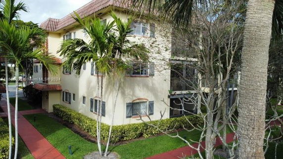 View of a multi-story residential building with a tiled roof and surrounding palm trees.