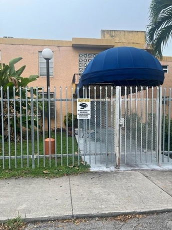 Front view of a two-story building with a gated entrance and blue canopy.