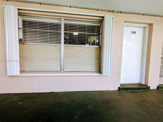 Front view of a building's entrance with a window and a door numbered 136.