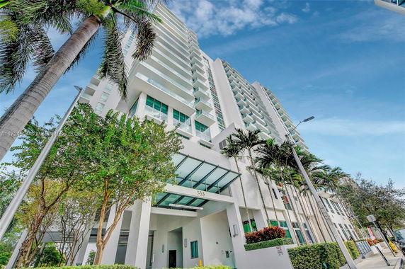 View from below of a modern high-rise building with multiple floors and balconies.
