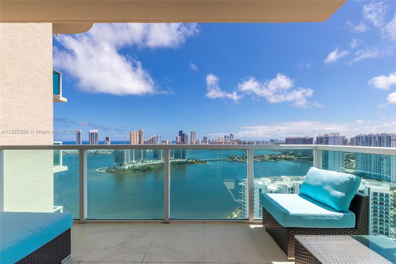View from a balcony with seating, overlooking a city skyline and body of water.