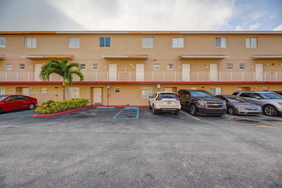 Front view of a multi-story building with a parking area in front.