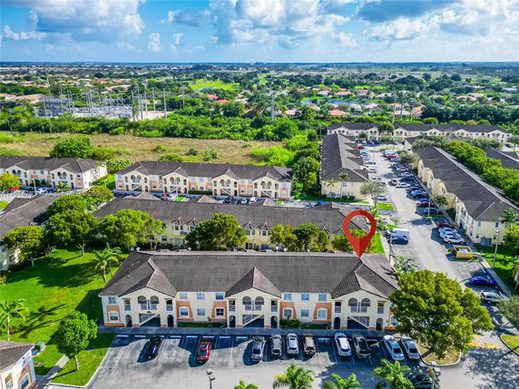 Aerial view of a residential complex with multiple two-story buildings and surrounding greenery.