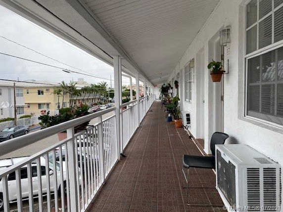 Outdoor walkway of a building with railing and potted plants.