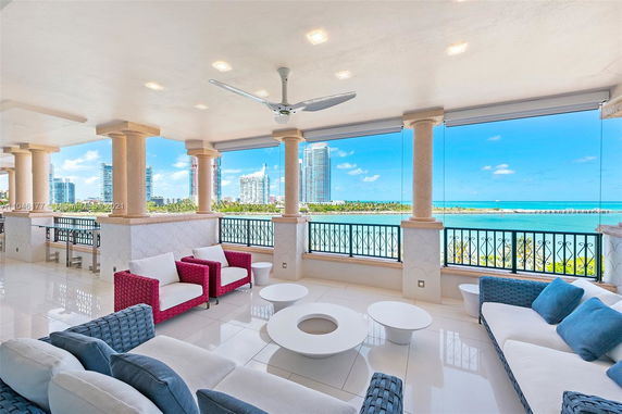 Covered outdoor terrace with comfortable seating overlooking ocean and cityscape.