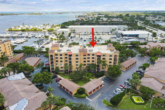 View of a multi-story apartment building with a flat rooftop, surrounded by other residential buildings and a marina nearby.