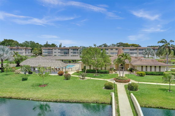 View of residential buildings with a landscaped garden and pond in the foreground.