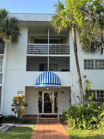Front view of a two-story residential building with a blue and white awning above the entrance.