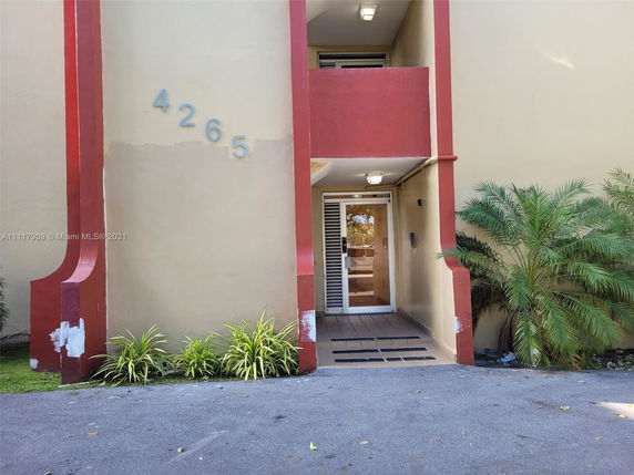 Front view of a building entrance with a number 4265 on the wall and a red accent design.