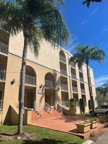 Front view of a multi-story residential building with balconies and palm trees.