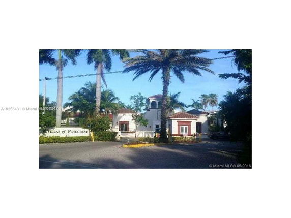 Front view of a residential complex entrance with palm trees.