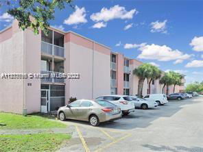 Front view of a multi-story residential building with parking spaces in front.
