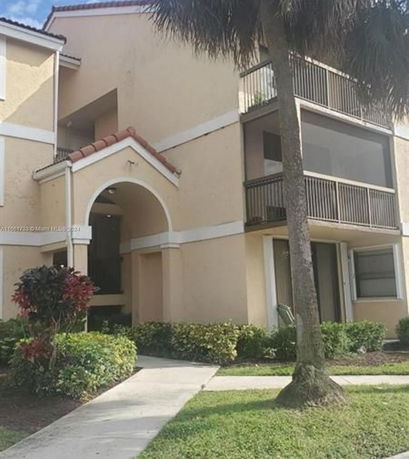 Front view of a multi-story residential building with balconies and a tiled roof.