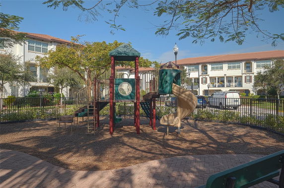 Children's playground with slides and climbing structures in front of residential buildings.