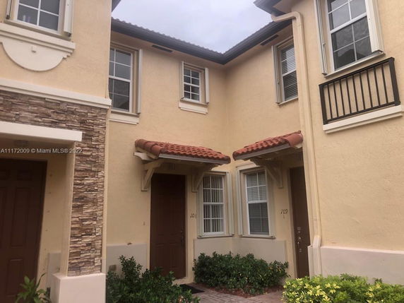 Front view of a two-story townhouse with beige walls and brown doors.
