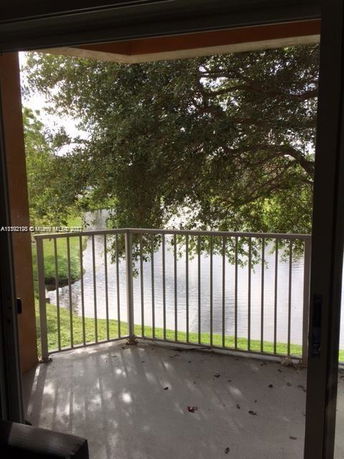 View from a balcony overlooking a pond and trees.