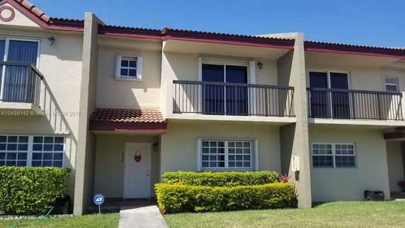 Front view of a two-story house with balconies and a tile roof.