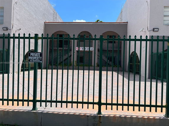 Front view of a building with a gated entrance and arched windows.