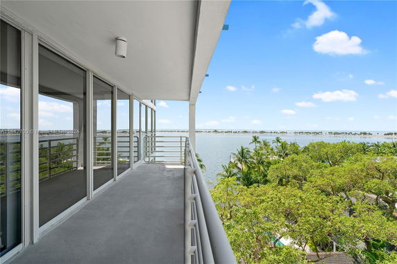 View from a balcony overlooking a body of water with trees and sky.