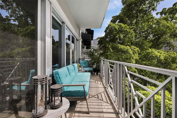 Balcony with seating area and view of trees and buildings.