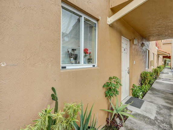 Exterior view of an apartment entrance with a beige facade, window with blinds, and a white door marked with A3.