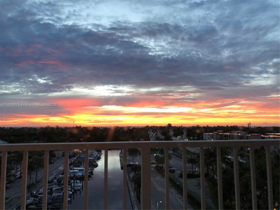 Panoramic view from a building showing a sunset over a marina and distant landscape.