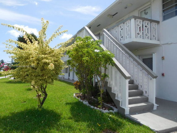 Front view of a two-story building with an external staircase and decorative railings.