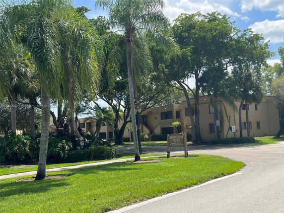 Front view of a two-story building with a flat roof and surrounded by trees.