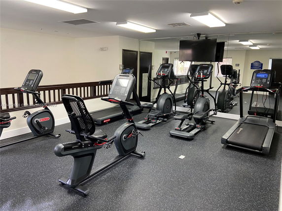 Indoor gym with exercise equipment including treadmills and stationary bikes.