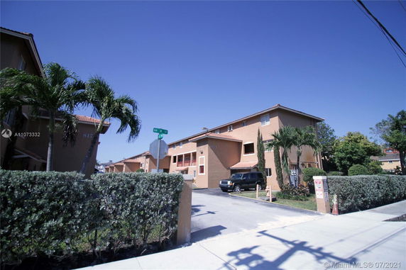 Front view of a multi-story residential building with parking area.