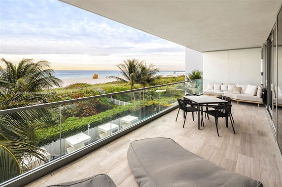 Ocean view from a modern balcony with seating area.