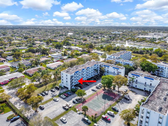 Aerial view of residential buildings and surrounding neighborhood with trees and roads.