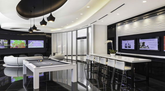 Indoor recreation area with pool table, seating, and multiple TVs.